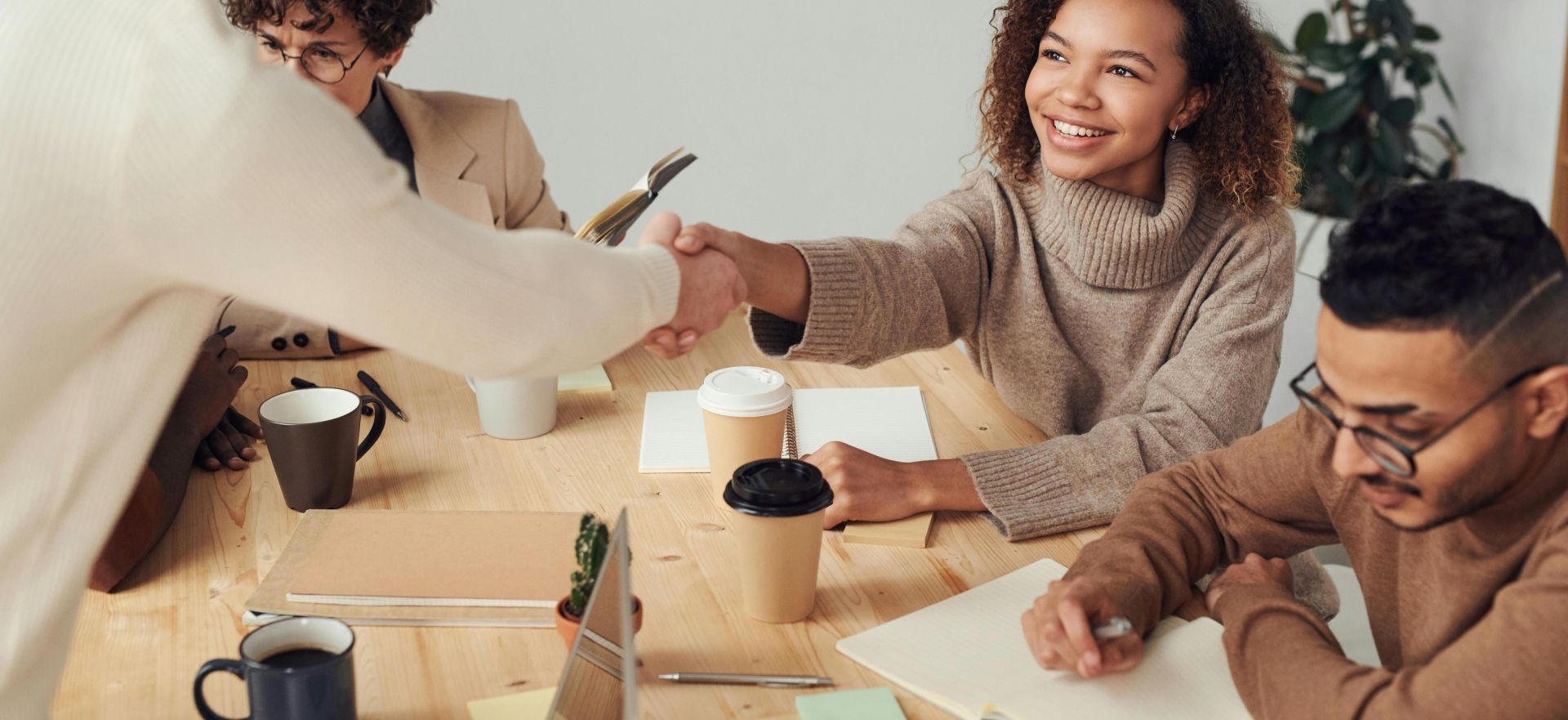Colleagues in a positive meeting, exchanging a handshake while discussing projects.