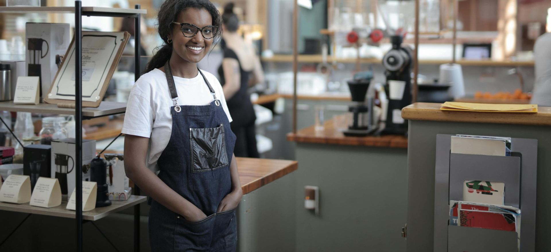 Smiling barista standing in a stylish café, showcasing entrepreneurial spirit.